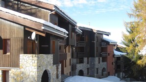 A multi-story building with stone and wooden facades, featuring balconies and arched doorways.
