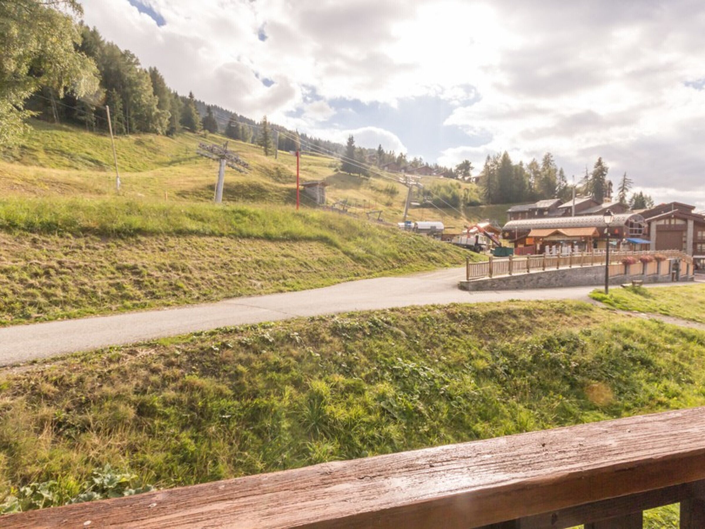 Eine Holzterrasse mit Blick auf eine ländliche Straße, im Hintergrund ein Gebäude.