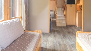 A cozy room with a bed, a small desk, and a staircase leading to a kitchen area.