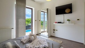 Una camera da letto moderna con un letto, una TV a parete e un balcone con vista sulla piscina.