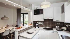 Cucina moderna con mobili bianchi, forno integrato, macchina del caffè e un'ampia finestra che permette l'illuminazione naturale.