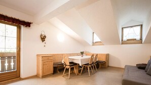 Ein Zimmer mit Esstisch, Stühlen, einer Couch, einem Holzkabinett und einem Fenster mit Blick.
