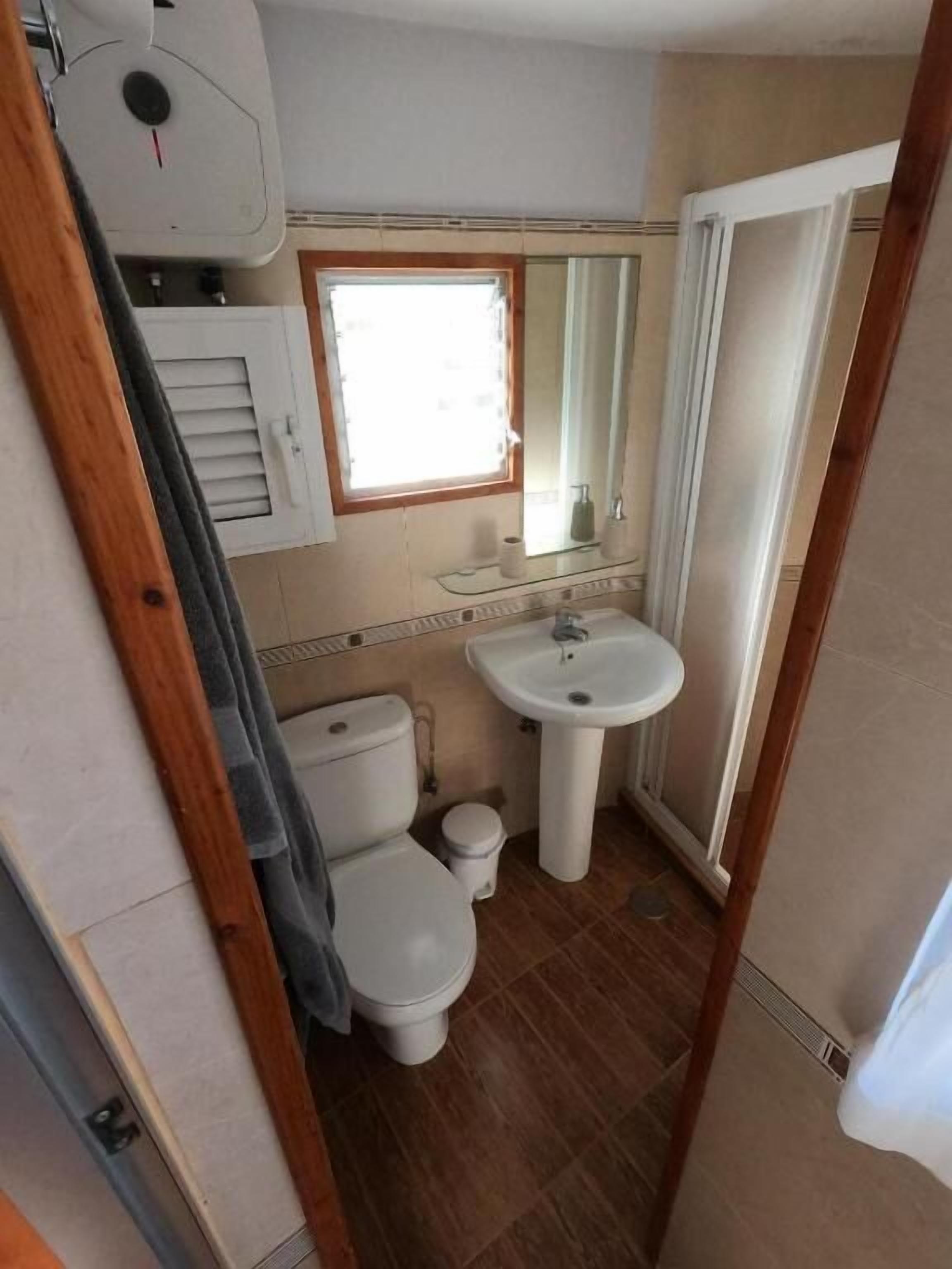 Un baño pequeño con inodoro, lavamanos y ventana.