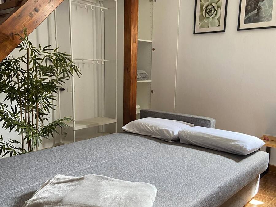 Un dormitorio con una cama, una escalera de madera, una planta y un armario.