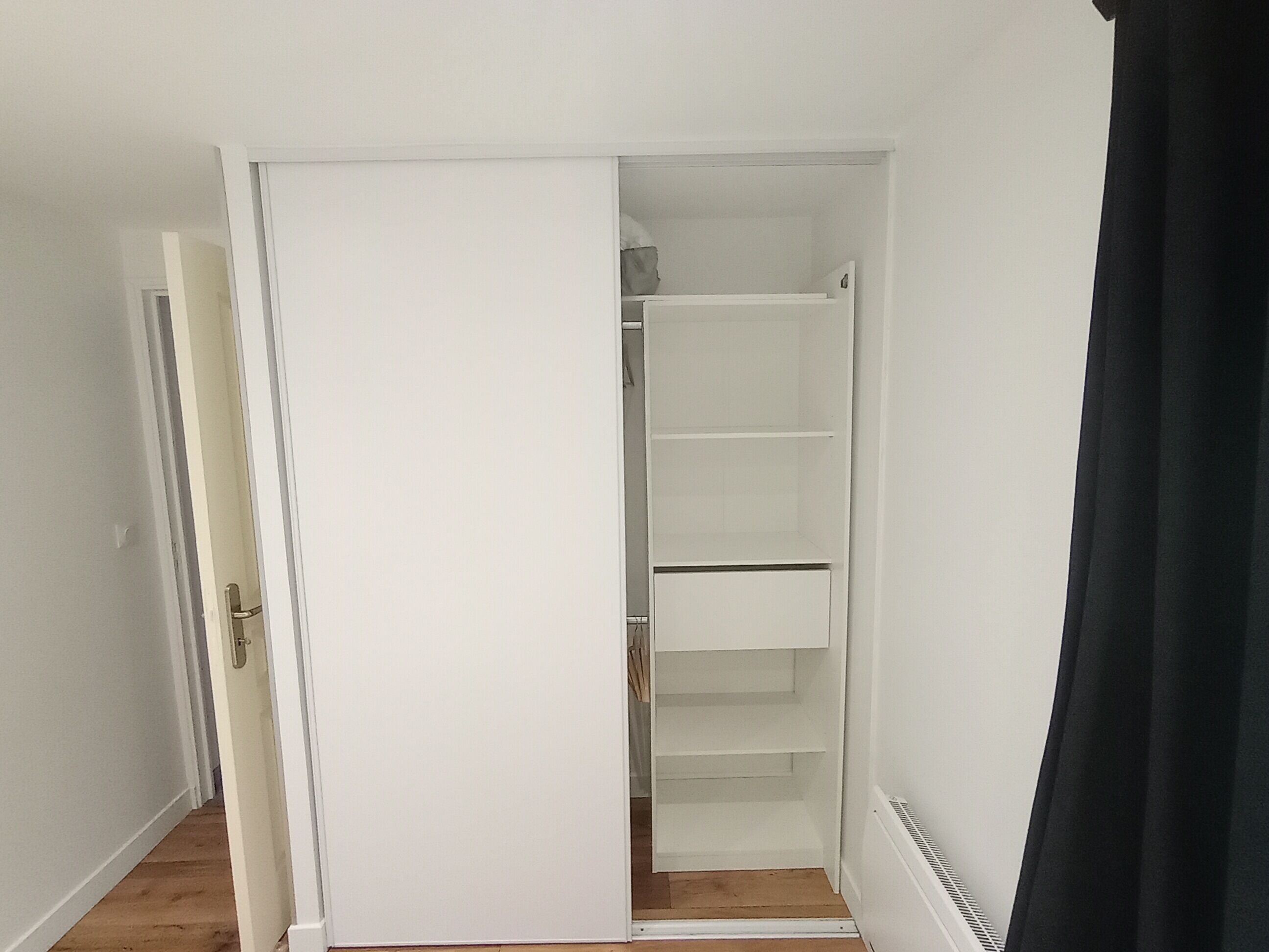 A room with a white wardrobe, a door, and a radiator.
