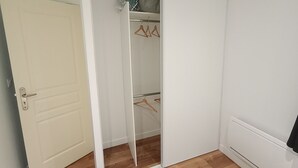 A white closet with wooden hangers and a plastic bag on the top shelf. - 6 Personnes / Proche Disney et Aéroport CDG (Annet-sur-Marne)