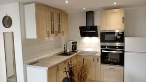 A modern kitchen with wooden cabinets, a built-in oven, a microwave, and a coffee maker. - 6 Personnes / Proche Disney et Aéroport CDG (Annet-sur-Marne)