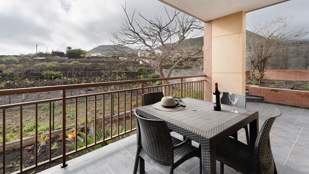 A balcony with a table and chairs, a bottle of wine, and a hat. - Holiday Home 'Casa Girdana' with Sea View, Private Terrace and Wi-Fi (Valverde)