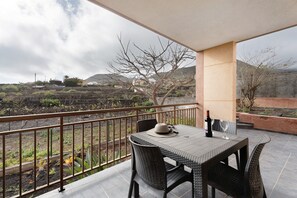 A balcony with a table and chairs, a bottle of wine, and a hat. - Holiday Home 'Casa Girdana' with Sea View, Private Terrace and Wi-Fi (Valverde)