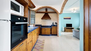 A compact kitchen with a microwave, oven, and wooden cabinets. - Holiday Home 'Casa Girdana' with Sea View, Private Terrace and Wi-Fi (Valverde)