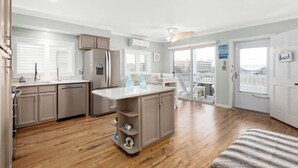 A spacious kitchen with a central island, wooden flooring, and a view of the city through large windows. - Nicely Renovated Two Bedroom Oceanside Condo (Ocean City)