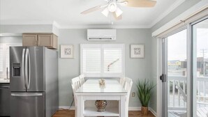 A modern kitchen with a stainless steel refrigerator, a white dining table with chairs, and a ceiling fan. - Nicely Renovated Two Bedroom Oceanside Condo (Ocean City)