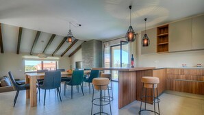 Une cuisine moderne dotée d’un îlot central, de tabourets de bar et d’un coin repas avec des chaises.