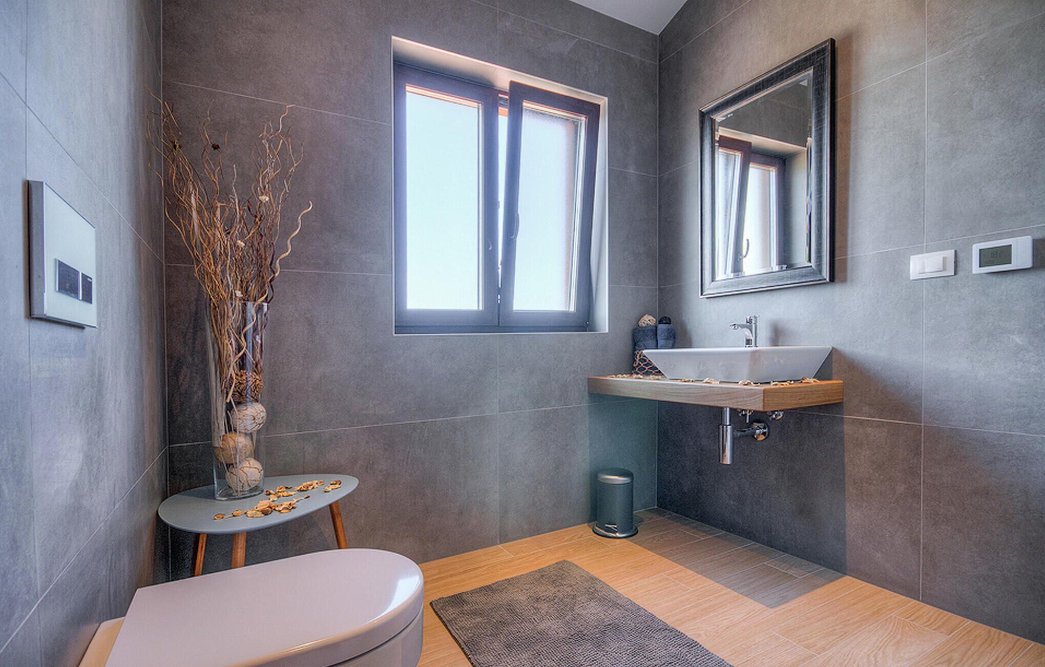 Een moderne badkamer met toilet, wastafel en raam.