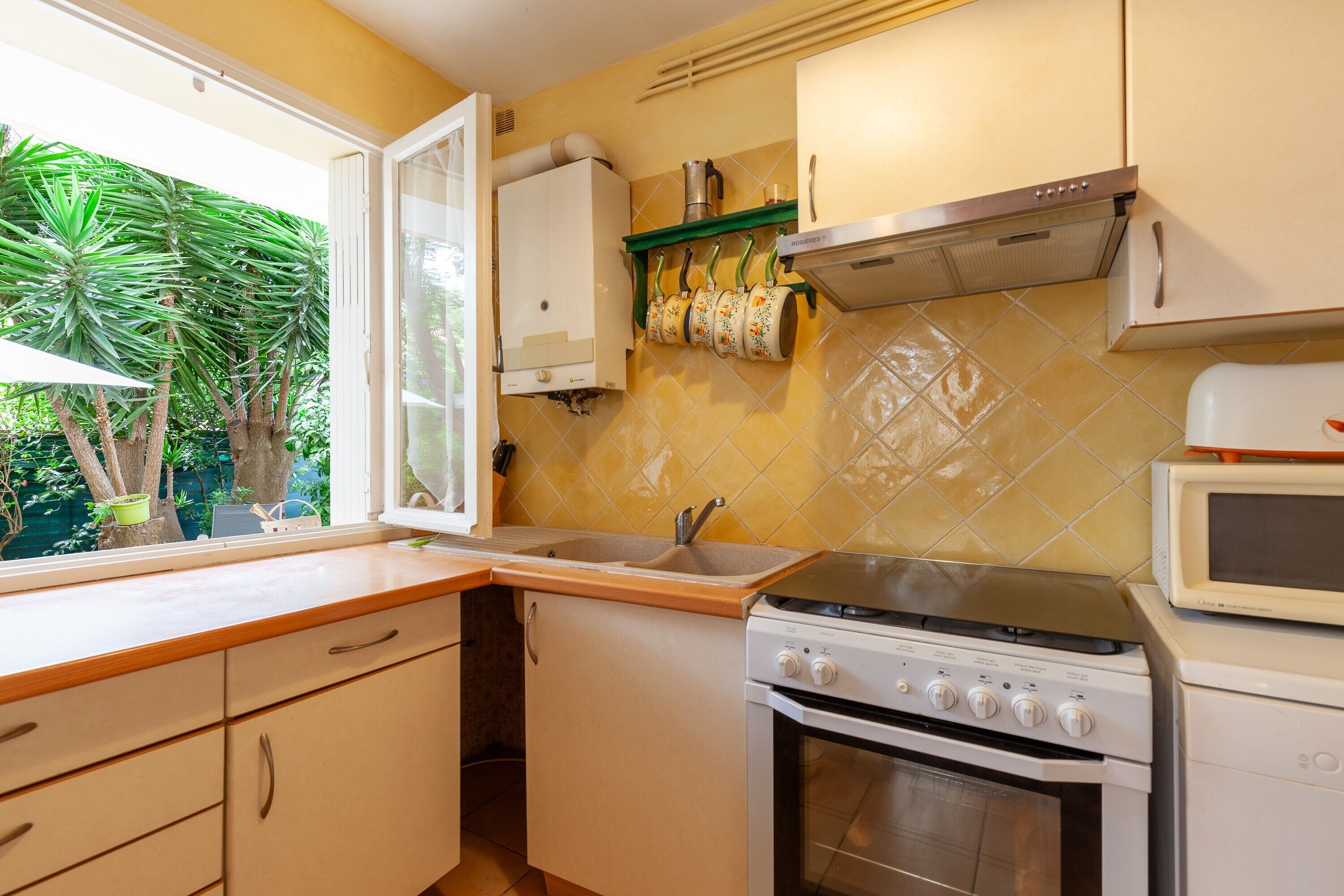 A kitchen with a stove, microwave, sink, and cabinets.