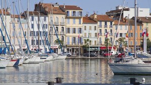 Un port de plaisance avec des bateaux amarrés, des bâtiments dotés de balcons et des drapeaux.