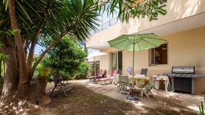 Une terrasse avec un barbecue, des sièges d’extérieur et un arbre.