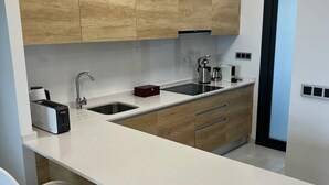 A modern kitchen with wooden cabinets, a white countertop, a built-in sink, and a toaster. - Apartment 'Sunset Waves' with Sea View, Wi-Fi and Air Conditioning (Benidorm)