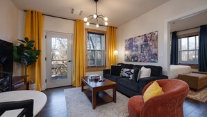 Una sala de estar con un sofá, un sillón, una mesa de centro y un cuadro en la pared.