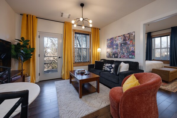 A living room with a sofa, armchair, coffee table, and a painting on the wall.