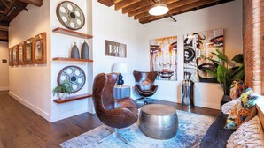 Una sala de estar moderna con vigas de madera a la vista, un reloj de pared redondo grande y muebles contemporáneos.