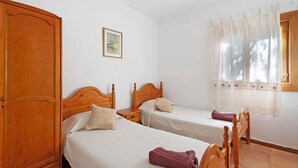 A bedroom with two wooden beds, a wardrobe, a nightstand, and a window with a curtain.