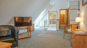 Une pièce de style « loft », dotée d’un téléviseur, d’un fauteuil en cuir, de meubles en bois et offrant une vue sur l’extérieur.