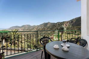 Un balcon avec une table, des chaises et une vue sur un paysage montagneux.