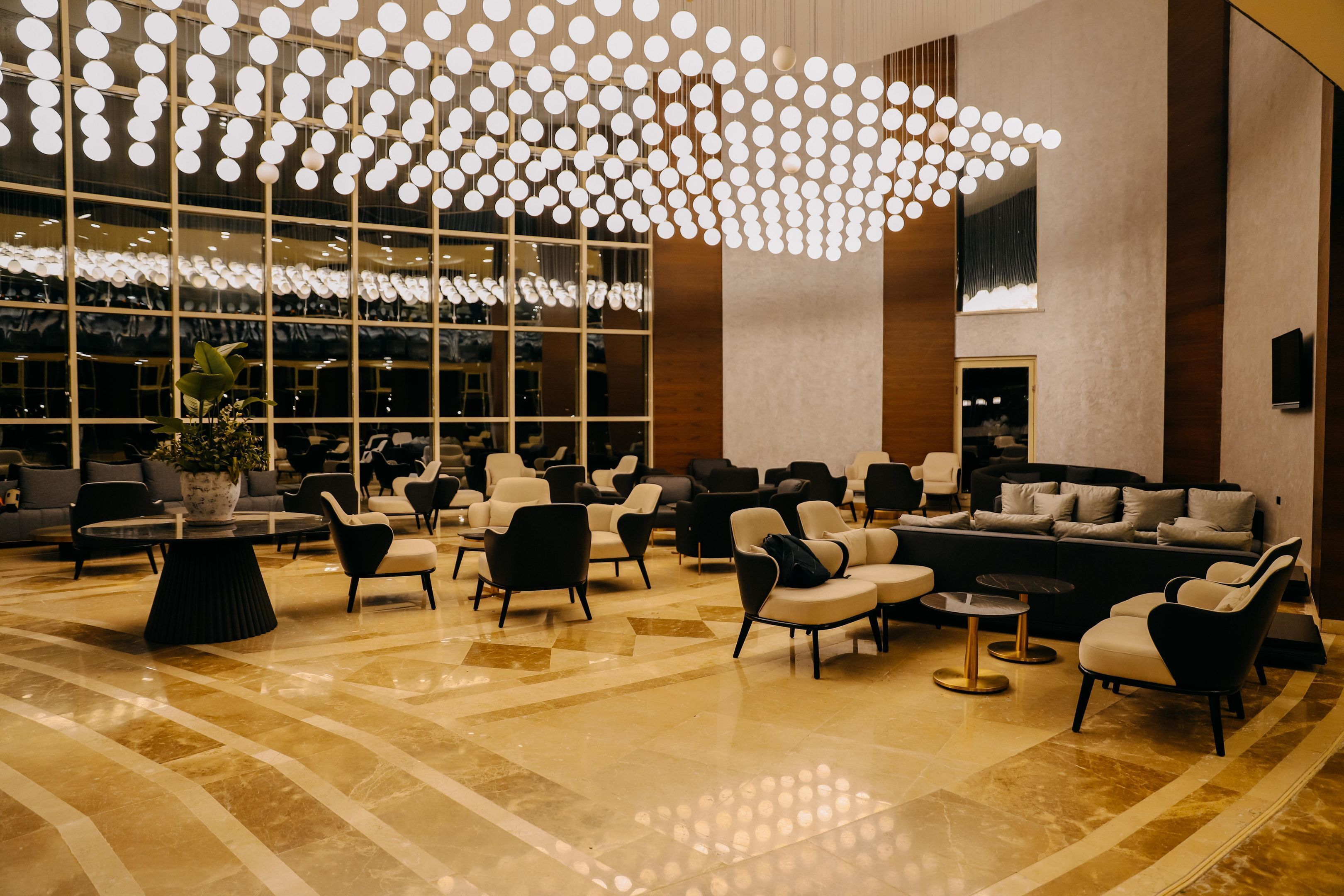 A spacious lobby with a modern chandelier, comfortable seating, and large windows.