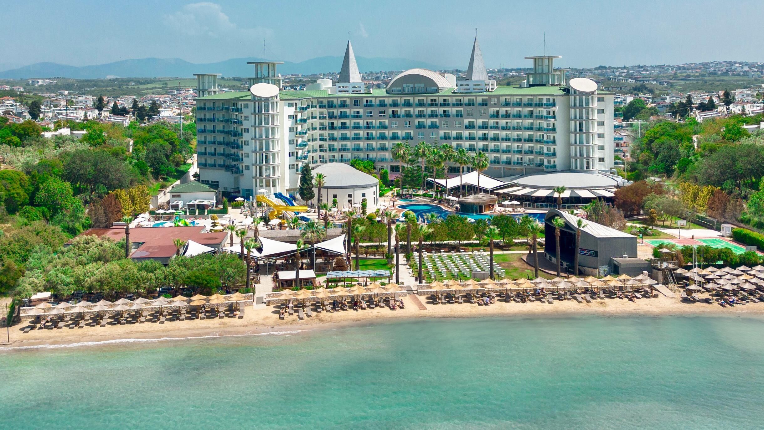 A resort with a large building, a pool, and a beach area.
