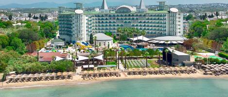 A resort with a large building, a pool, and a beach area.