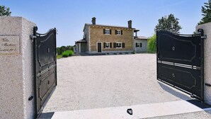 Une villa avec une allée pavée menant à une entrée fermée par un portail.