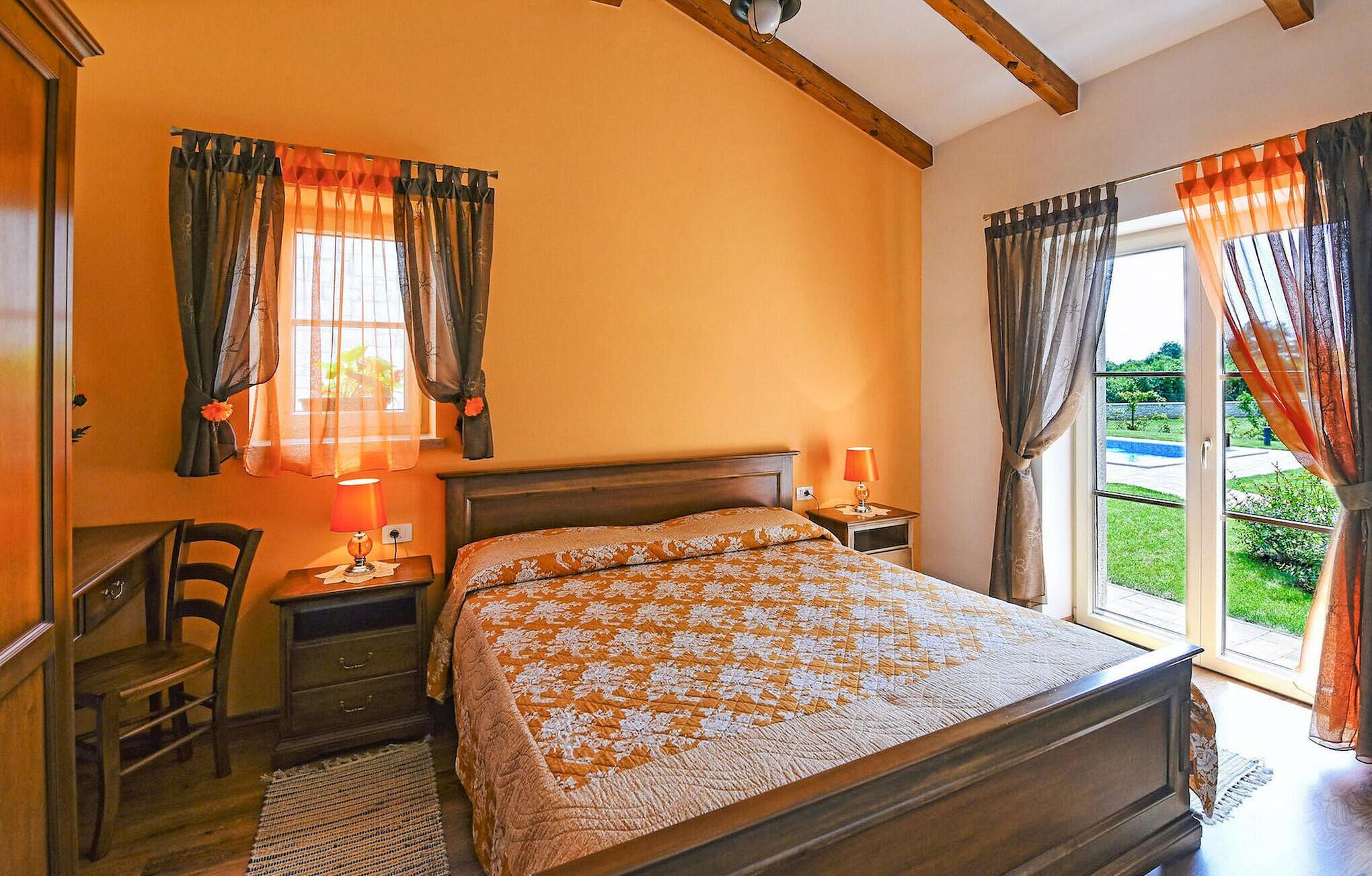 A bedroom with a wooden bed, two bedside tables, a chair, and a view of a garden through a sliding door.
