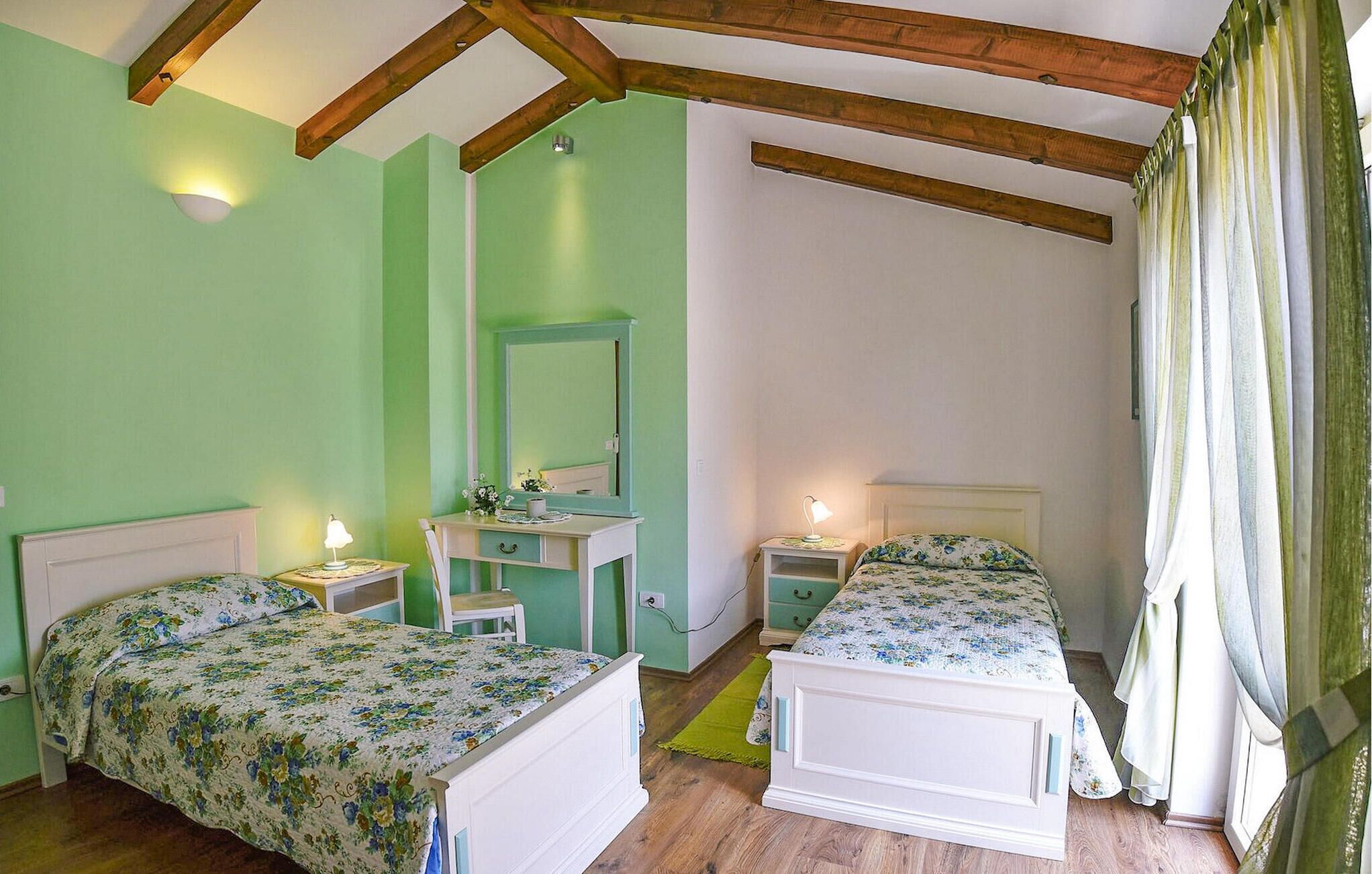 Ein Schlafzimmer mit zwei Betten, einem Schreibtisch und einem Spiegel.