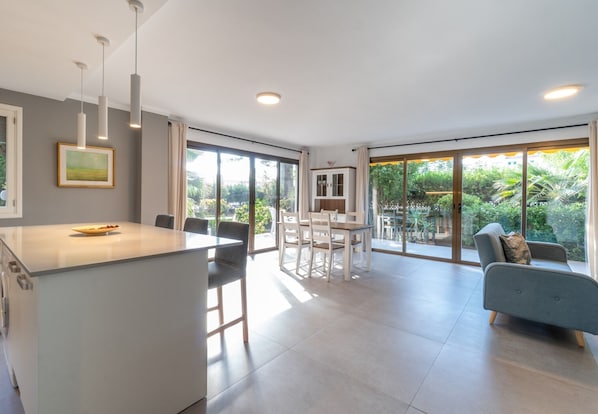 A modern kitchen with a central island, dining area, and a sofa.