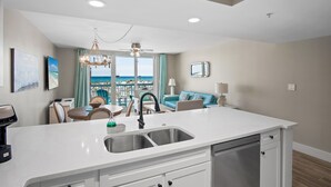 Een moderne keuken met een centraal eiland, een eetgedeelte met uitzicht en een zithoek met een bank en een lamp.