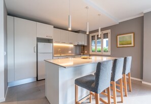 Une cuisine moderne dotée d’un îlot central, de luminaires suspendus et d’un coin repas avec des chaises.