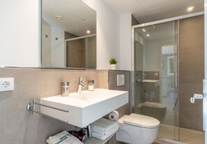 A modern bathroom with a white sink, mirror, and toilet, a glass shower enclosure, and a towel rack. - Apartment 'Apartamento Ponent 7' with Private Terrace, Wi-Fi and Air Conditioning (Cala Ratjada)