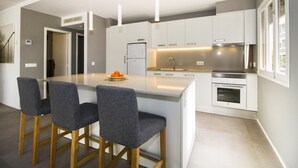 A modern kitchen with a central island, bar stools, a refrigerator, oven, and pendant lighting. - Apartment 'Apartamento Ponent 7' with Private Terrace, Wi-Fi and Air Conditioning (Cala Ratjada)