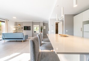 Et moderne køkken med en lang bordplade, en blå sofa og et spiseområde.