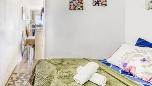 A bedroom with a bed, pillows, a green quilted bedspread, and two wall art pieces. - Apartment 'Les Embruns' with Sea View, Private Terrace and Balcony (Empuriabrava)