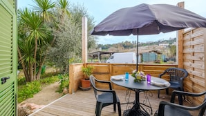 An outdoor patio with a table, chairs, and a large umbrella. - Apartment 'Vallon Des Prés' with Private Terrace, Shared Garden and Wi-Fi (Villeneuve-Loubet)