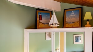 Una habitació amb una obra d'art marina emmarcada, un model de veler petit i una làmpada sobre una prestatgeria.