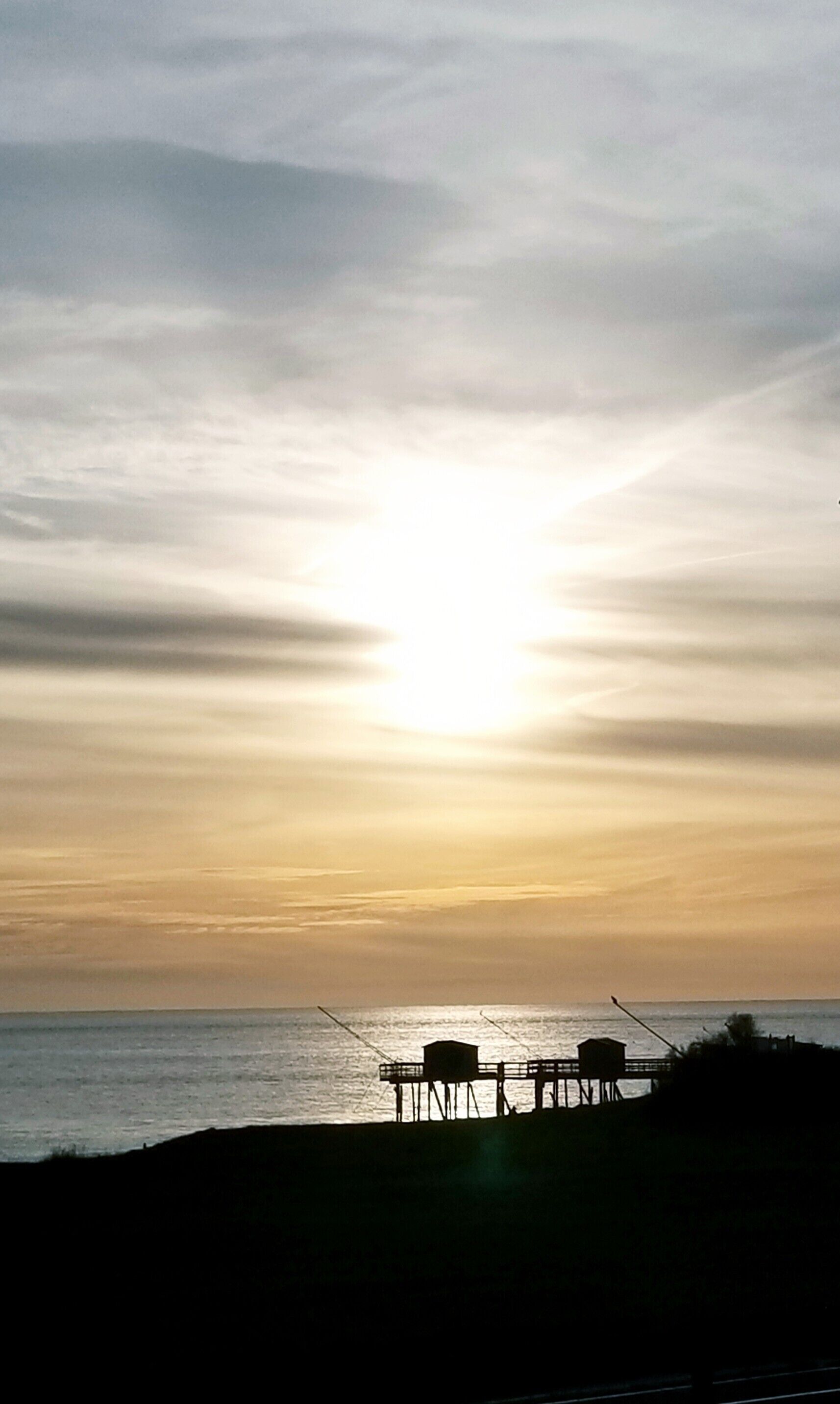 A pier extending into the water with a structure on it.