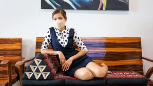 A person sitting on a wooden bench with a colorful abstract painting above. - No.9 hostel kanchanaburi (Kanchanaburi)