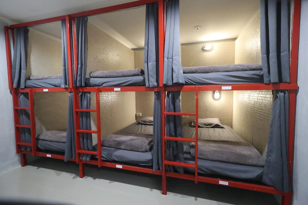 Habitación tipo dormitorio con literas, cada una con una escalera, y una pequeña mesa con lámpara.
