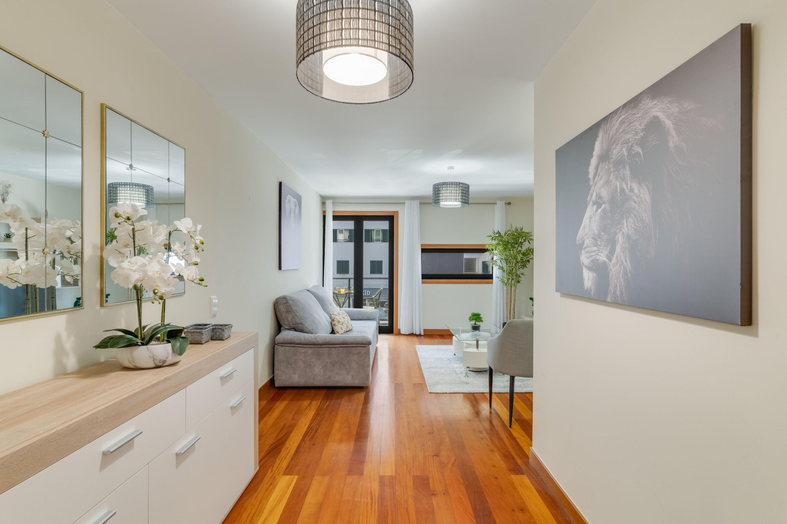 Een moderne woonkamer met een bank, een eethoek, een grote spiegel en een schilderij aan de muur.