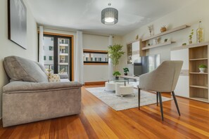 Een moderne woonkamer met een bank, fauteuil, televisie en planten op de planken.