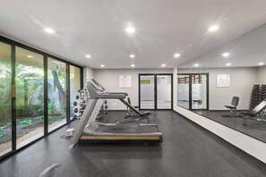 A gym with treadmills, weight machines, and a large window with a view of greenery.