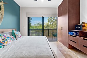 A bedroom with a bed, a wardrobe, a balcony with a view of trees, and a macrame wall hanging. - Spectacular Penthouse: Private  Rooftop and Pool (Tulum)